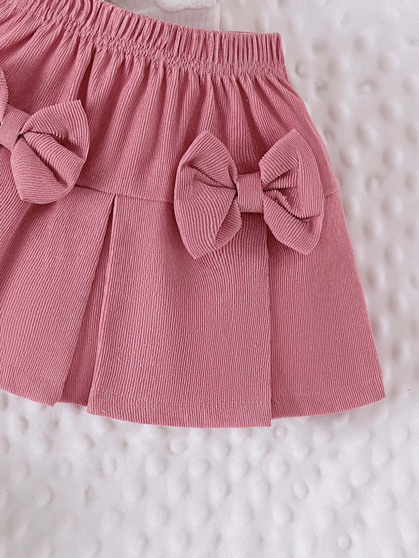 Pink skirt with large bows on a textured white background