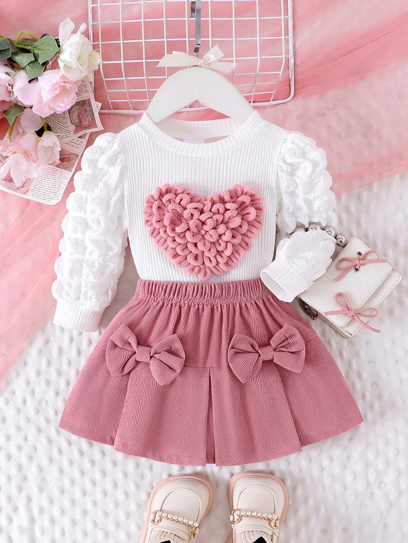 Children's outfit with white long-sleeve top and pink skirt on a pink background
