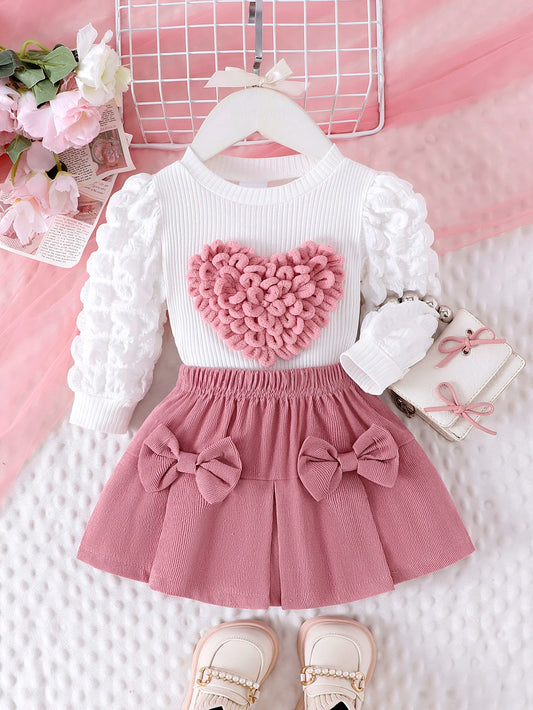 Children's outfit with white long-sleeve top and pink skirt on a pink background